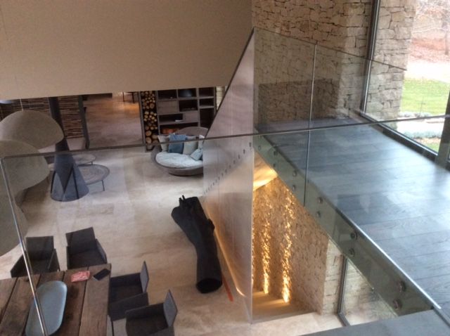 Mezzanine sur salon en passant par une coursive béton, avec une rampe de verre en protection